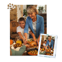 1000 piece Thanksgiving photo puzzle featuring a grandmother and grandson serving turkey at a family dinner, shown with its matching puzzle box