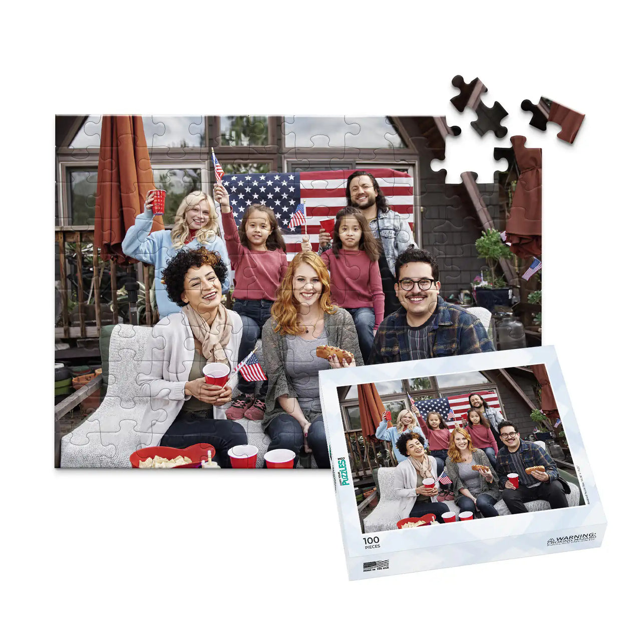 100 piece 4th of July photo puzzle featuring a family celebrating with American flags and hot dogs, shown with its matching puzzle box