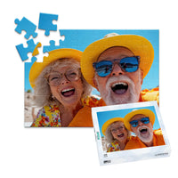 48 piece personalized couple puzzle featuring a joyful older couple wearing sun hats at the beach, shown with its matching puzzle box