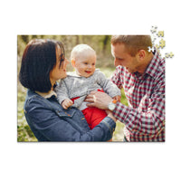 500 piece personalized puzzle for new parents showing a smiling mother and father holding their baby outdoors.