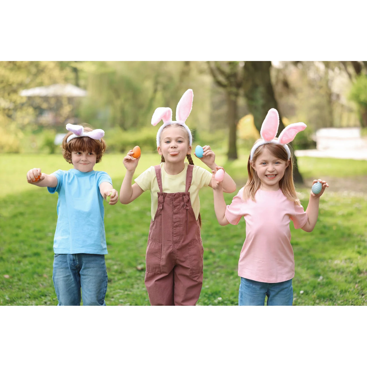 Easter Photo Puzzle of three children wearing bunny ears and holding colorful Easter eggs in a sunny garden, landscape orientation.